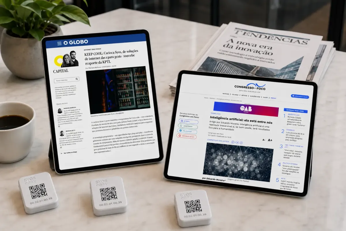 Tablets exibindo matérias sobre a SyOS ao lado de jornais impressos e três sensores SyOS Easy
